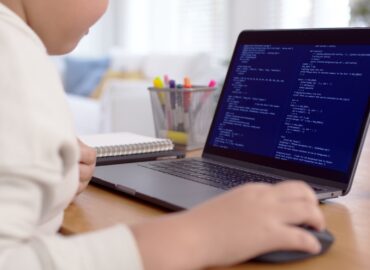 Back rear view of young asian kids boy using computer laptop coding python language