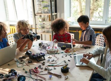 Diverse school children students group building robotic cars using computers.